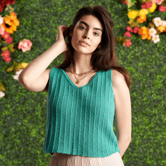 The Summer Vertical Ridges top is turquoise. It is in garter stitch with lines of vertical knit ridges. It has a shallow v neck.